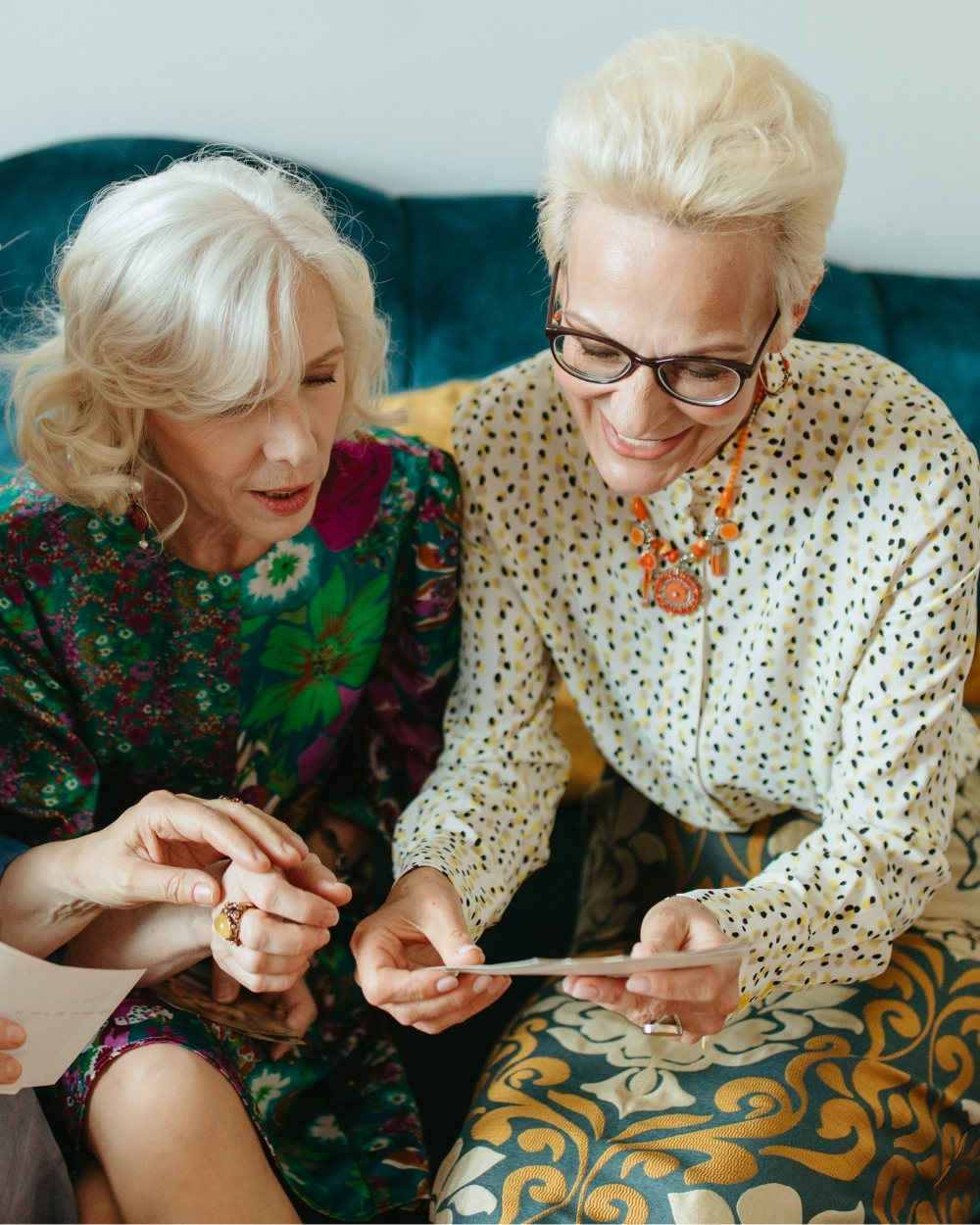 A two-story building with a landscaped yard, surrounded by trees and parked cars, under a clear blue sky.